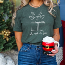 Bookish Reindeer T-Shirt - A white woman is modelling a dark teal t-shirt with a white line art design of a reindeer reading a book. Below the design in curly writing are the words "oh, what fun".