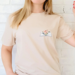 Reading Pocket Design T-shirt - A model wears a cream t-shirt with a small printed pocket design of an open book with flowers between the pages.