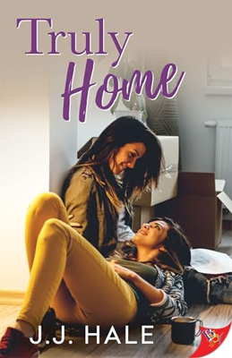 Disabled and Neurodivergent Books out in March 2024 - Truly Home by J.J. Hale - A book cover featuring a photograph of two white skinned women sitting close together in a room with white walls and a wood floor. One woman sits with her back to a wall, her head leaning forward towards the other woman who is lying in her lap. Her dark shoulder-length hair is falling forward. She is wearing a dark jacket over a light top. The other woman is lying with her head propped up in her companion's lap, her legs bent upwards at the knees. She has dark hair, and is wearing a white and black patterned long-sleeved top over a dark top and bright yellow pants. She is looking up at the other woman. Both of them are smiling at each other. Behind them, a pile of cardboard boxes can be seen, some open and others taped shut. The title, Truly Home, is printed in purple text at the top of the cover. The author's name is printed at the bottom in a white font. The bottom right corner has a red triangle logo of the publisher.