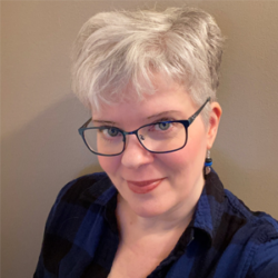 About the author: Cait Gordon - A close-up of Cait Gordon, standing in front of a beige background. She is a white woman with short silver hair cropped closely on the sides. She is wearing dark teal metallic rimmed glasses with rhinestones on the side. She has blue-green eyes, coral lipstick, and is wearing silver hook earrings with black and electric blue beads. Her shirt is plaid with black and electric blue.