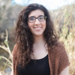 About the Author: Melissa Bashardoust - A woman with pale skin and long curly dark hair. She is wearing thick framed round glasses, a black top and a short-sleeved brown knit cardigan. She is standing outside surrounded by nature, and is looking directly at the camera smiling. The image is cropped to show her head and shoulders.